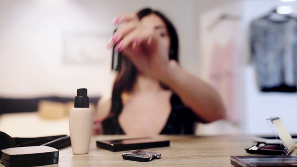 selektywne skupienie kobiety kładąc szminkę na stole z kosmetykami dekoracyjnymi - Materiał filmowy, wideo