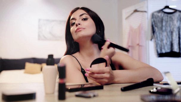 enfoque selectivo de la mujer aplicando polvo facial con cepillo cosmético
 - Metraje, vídeo