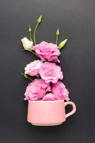Cup with beautiful fresh flowers on dark background - Photo, Image