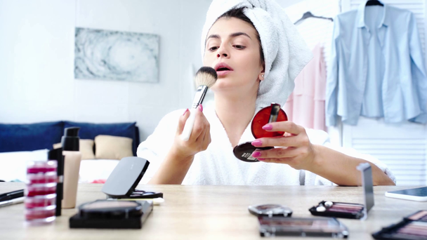 szelektív hangsúly a nő alkalmazó arc por kozmetikai kefével reggel - Felvétel, videó