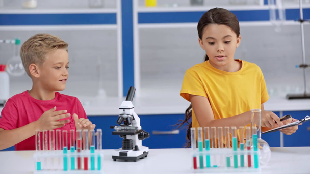 lindos niños añadiendo líquidos cerca del microscopio
  - Imágenes, Vídeo