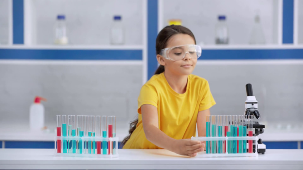 rack focus of kid putting test tubes on table  - Metraje, vídeo