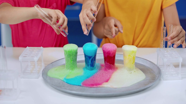 vista recortada de los niños agregando agua en líquidos coloridos
  - Imágenes, Vídeo