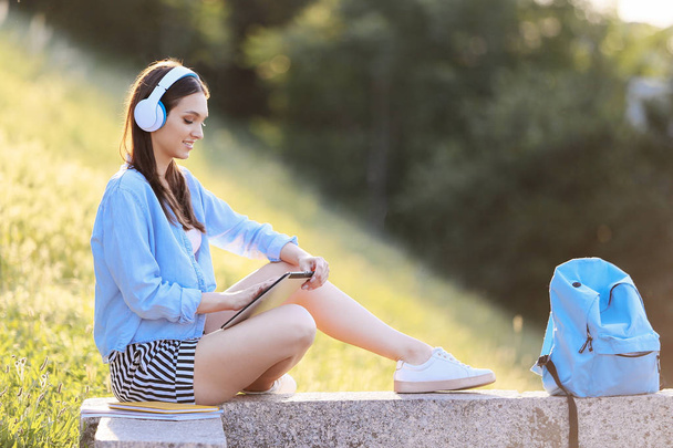 Όμορφη γυναίκα φοιτητής με tablet υπολογιστή ακούγοντας μουσική σε εξωτερικούς χώρους - Φωτογραφία, εικόνα