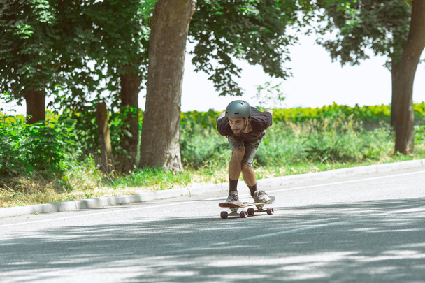 Skateboarder doing a trick at the citys street in sunny day - Zdjęcie, obraz