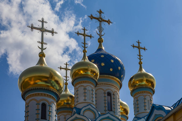 Blue and golden domes of an orthodox temple against a cloudy sky - Fotó, kép