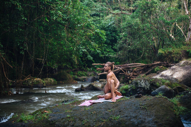 Yoga practice and meditation in nature. Man practicing near river - Fotó, kép