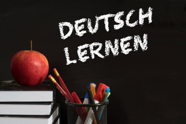 School books, apple and chalk board with the slogan german learning - Foto, Imagen