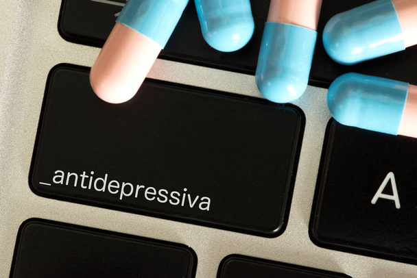 Comprimidos e um computador com o botão antidepressivos
 - Foto, Imagem