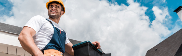 plano panorámico de reparador feliz en casco y uniforme
  - Foto, imagen