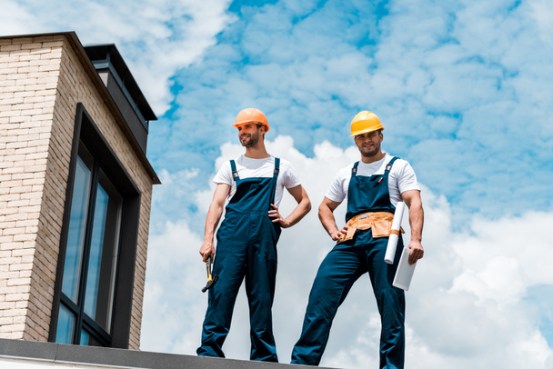 low angle view of handsome repairmen standing with hands on hips  - Photo, Image
