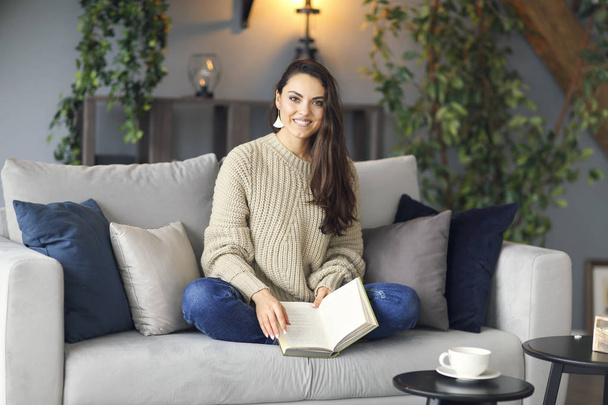 Young happy brunette woman with book wearing sweater  - Fotografie, Obrázek
