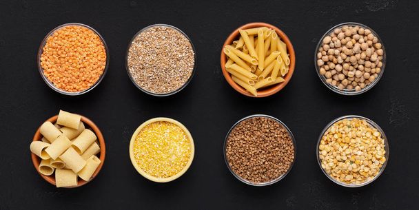 Getreide und Nudeln reich an Kohlenhydraten in Tellern auf schwarz - Foto, Bild