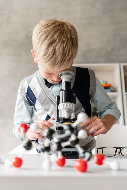 Little schoolboy in casual clothes looks in microscope - Photo, image