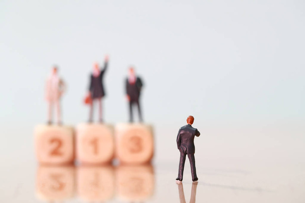 Miniatyyri ihmiset: liikemies etsii ja ajattelee kilpailija seisoo puinen palkintokorokkeella (Financial and Business kilpailun käsite
 - Valokuva, kuva
