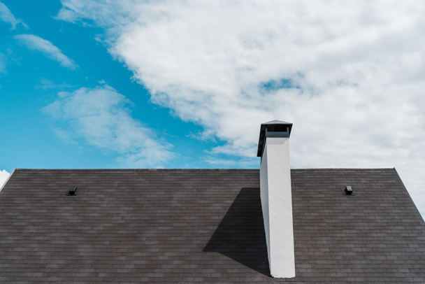 έρπητα ζωστήρα στη στέγη σε νέο πολυτελές σπίτι ενάντια στο γαλάζιο του ουρανού με σύννεφα  - Φωτογραφία, εικόνα