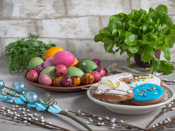 Пасхальное угощение из цветных яиц, окрашенных пряников, свежих трав и ивовых веточек
 - Фото, изображение