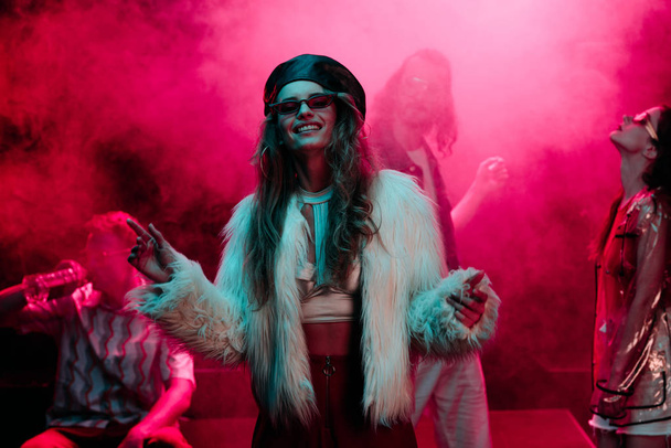 cheerful girl dancing in nightclub with pink smoke - Foto, imagen