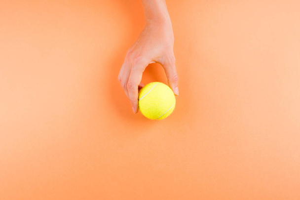 Pelota de tenis en naranja en manos de mujeres
 - Foto, Imagen