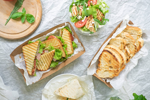 хлеб из ветчины с овощным салатом и помидорами на столе и бумаге
 - Фото, изображение