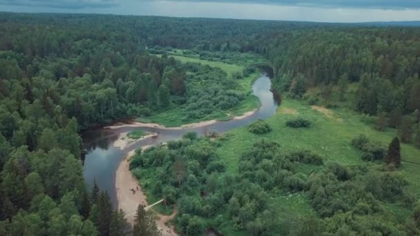 Luchtfoto van de prachtige Russische rivier gelegen tussen groene weide en gemengde bos tegen bewolkte hemel in zomerdag. Stock footage. Schilderachtig uitzicht van bovenaf van de Russische natuur - Video