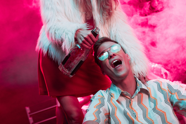 girl with alcohol near man in sunglasses with lsd on tongue in nightclub  - Фото, изображение