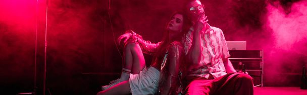 panoráma lövés az ember és a fiatal nő ül együtt a rave Party in nightclub - Fotó, kép