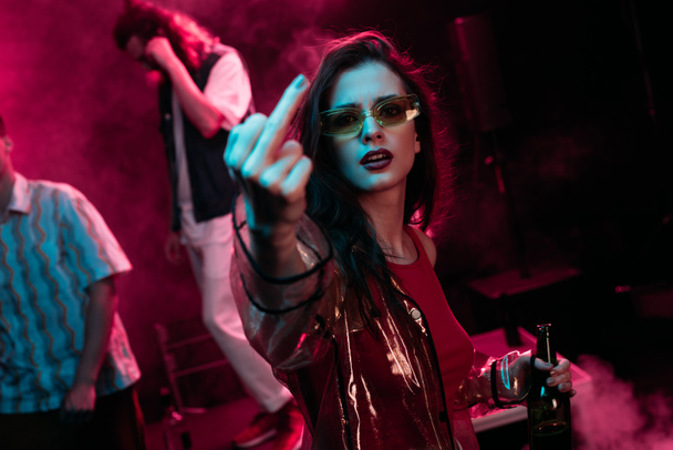 girl with beer showing middle finger in nightclub during rave - Zdjęcie, obraz