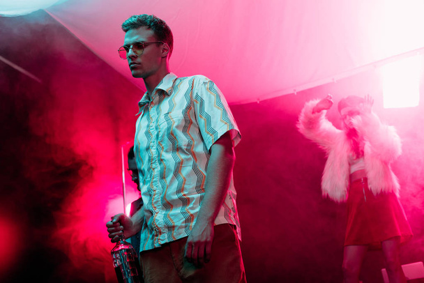 man in sunglasses with bottle of alcohol during rave in nightclub - Φωτογραφία, εικόνα