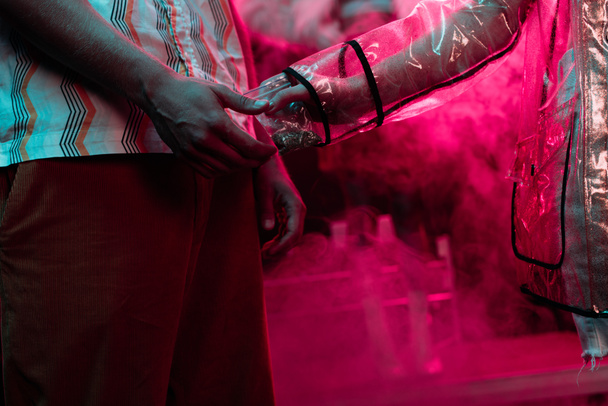 Ausgeschnittene Ansicht einer Frau, die einem Mann in einem Nachtclub Unkraut in einer Plastiktüte mit Reißverschluss gibt - Foto, Bild