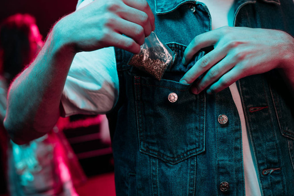 Vágott kilátás az ember elhelyezés a zsebében marihuána a szórakozóhely - Fotó, kép