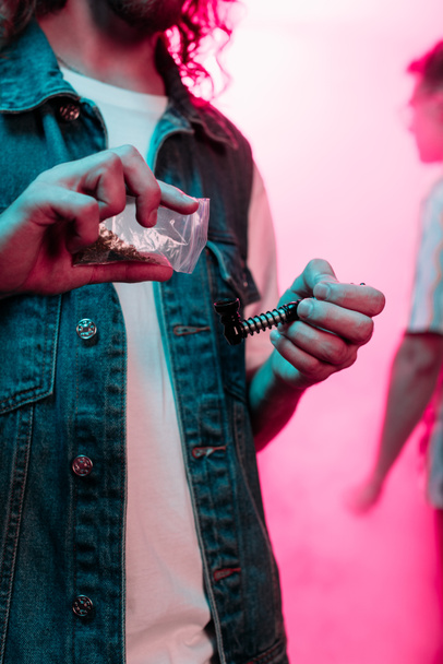 Oříznutý pohled na člověka, který dává marihuanu do dýmky v nočním klubu - Fotografie, Obrázek