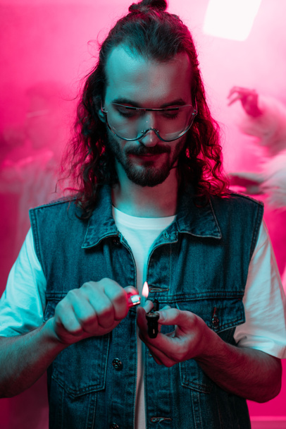 hombre guapo iluminación pipa de fumar con marihuana en discoteca
 - Foto, imagen