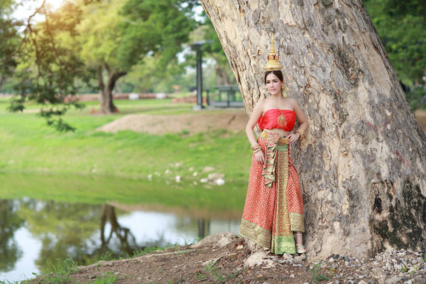 Молода Азіатська мода дівчина носить тайський традиційний костюм з красою особи стоячи поруч з великими зеленими деревами в природі на відкритому повітрі (використовуючи для фону) - Фото, зображення