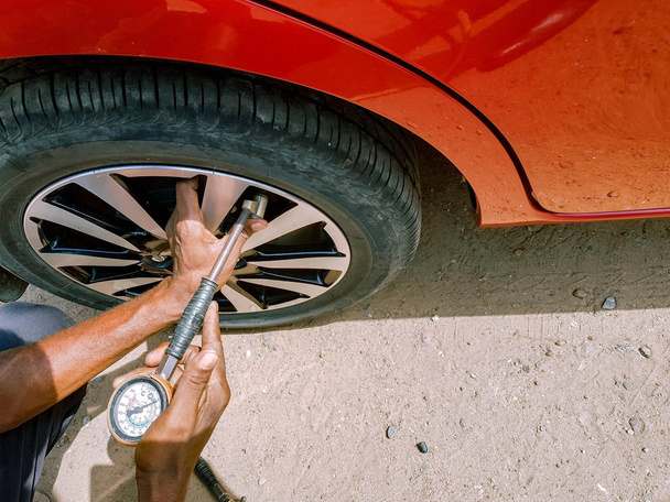controlo da pressão do ar com um manómetro num pneu traseiro de um automóvel à mão do mecânico
 - Foto, Imagem