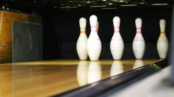 Vista di birilli da bowling in piedi alla fine della pista da bowling e palla da bowling rotolando sulla superficie di legno in un club sportivo. Weekend sportivi divertenti in un bowling
 - Filmati, video