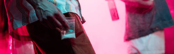 tiro panorámico de hombre sosteniendo drogas en bolsa de cremallera de plástico en discoteca
 - Foto, Imagen