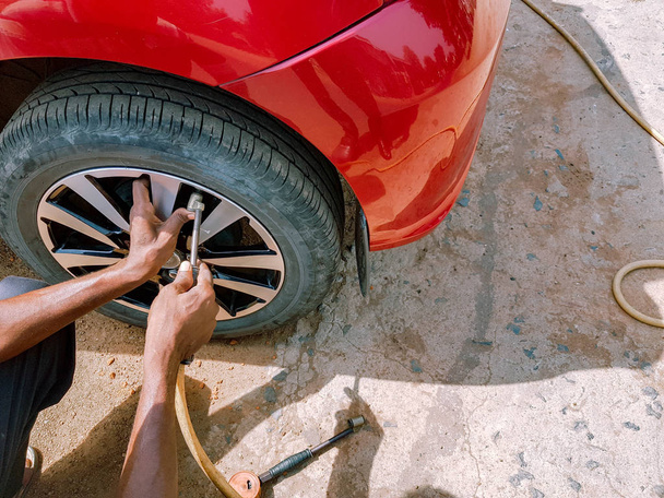 enchimento de ar num pneu da frente de um automóvel para manter a pressão do ar
 - Foto, Imagem
