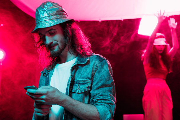άνθρωπος χρησιμοποιώντας smartphone κατά τη διάρκεια ρέιβ πάρτι σε νυχτερινό κέντρο - Φωτογραφία, εικόνα