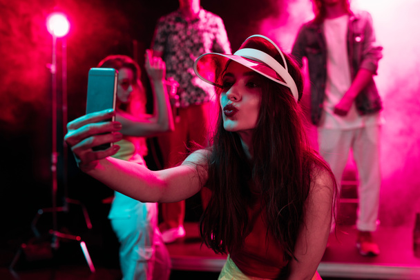дівчина кидає губи і приймає селфі на смартфон під час вечірки в нічному клубі
 - Фото, зображення