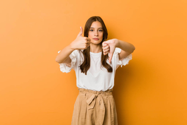 Young caucasian woman showing thumbs up and thumbs down, difficult choose concept - Photo, Image