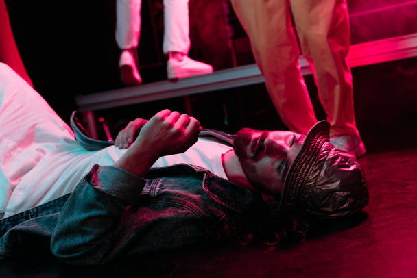 sick man lying on floor in nightclub with dramatic lighting - Фото, зображення