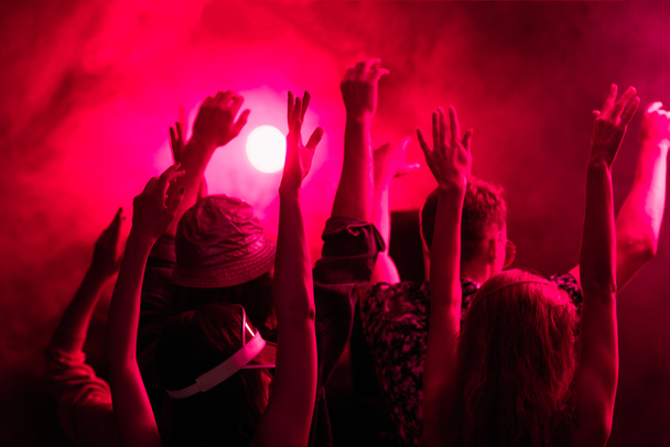 vista posterior de las personas con las manos levantadas durante la fiesta rave en el club nocturno
 - Foto, Imagen