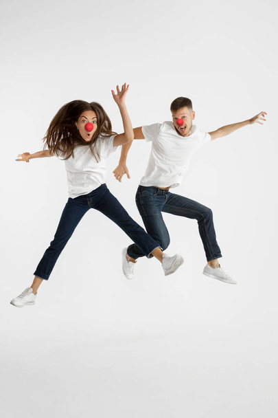 Portrait of beautiful couple celebrating red nose day on white studio background - Fotoğraf, Görsel
