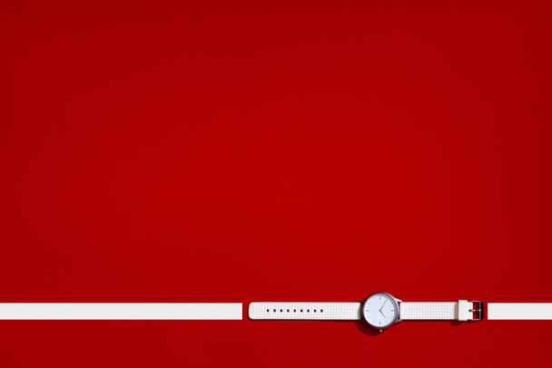 Relógio de silicone de design moderno branco. Conceito de tempo inteligente. Mosaico vista superior flat lay. Fundo de textura vermelha. Espaço de cópia lugar para texto
 - Foto, Imagem