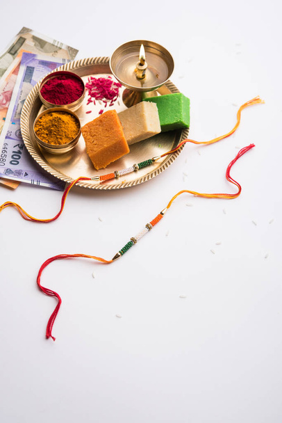Tricolor Rakhi y dulces para el Día de la Independencia / Raksha Bandhan que se encuentra en el mismo día en 2019, puja thali decorado con diya, haldi / kumkum y moneda india como regalo
 - Foto, Imagen
