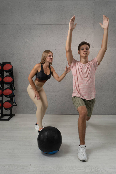Young man working out with personal trainer at the gym. Exercises with ball - Foto, afbeelding