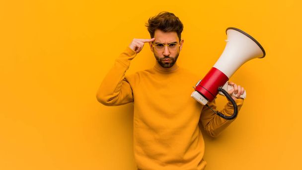 Young man holding a megaphone doing a concentration gesture - Photo, Image