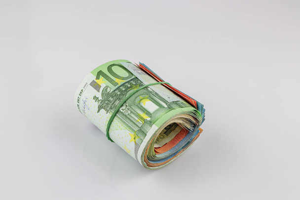Roll of 100, 50, 20 and 10 euro banknotes with a rubber band, is - Foto, imagen