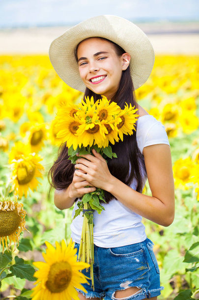 Portrait of a young beautiful girl in a field of sunflowers - Φωτογραφία, εικόνα